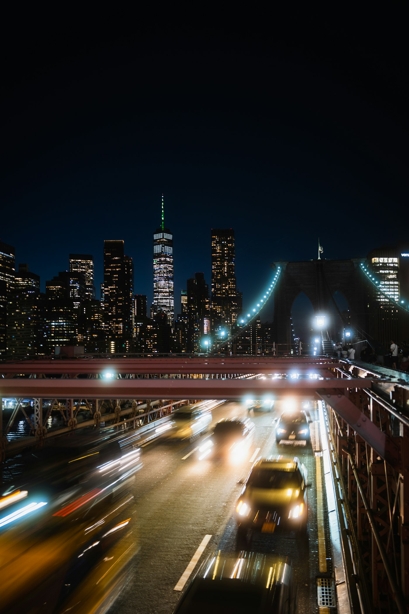 Traffic crossing a New York bridge at night with the skyline behind