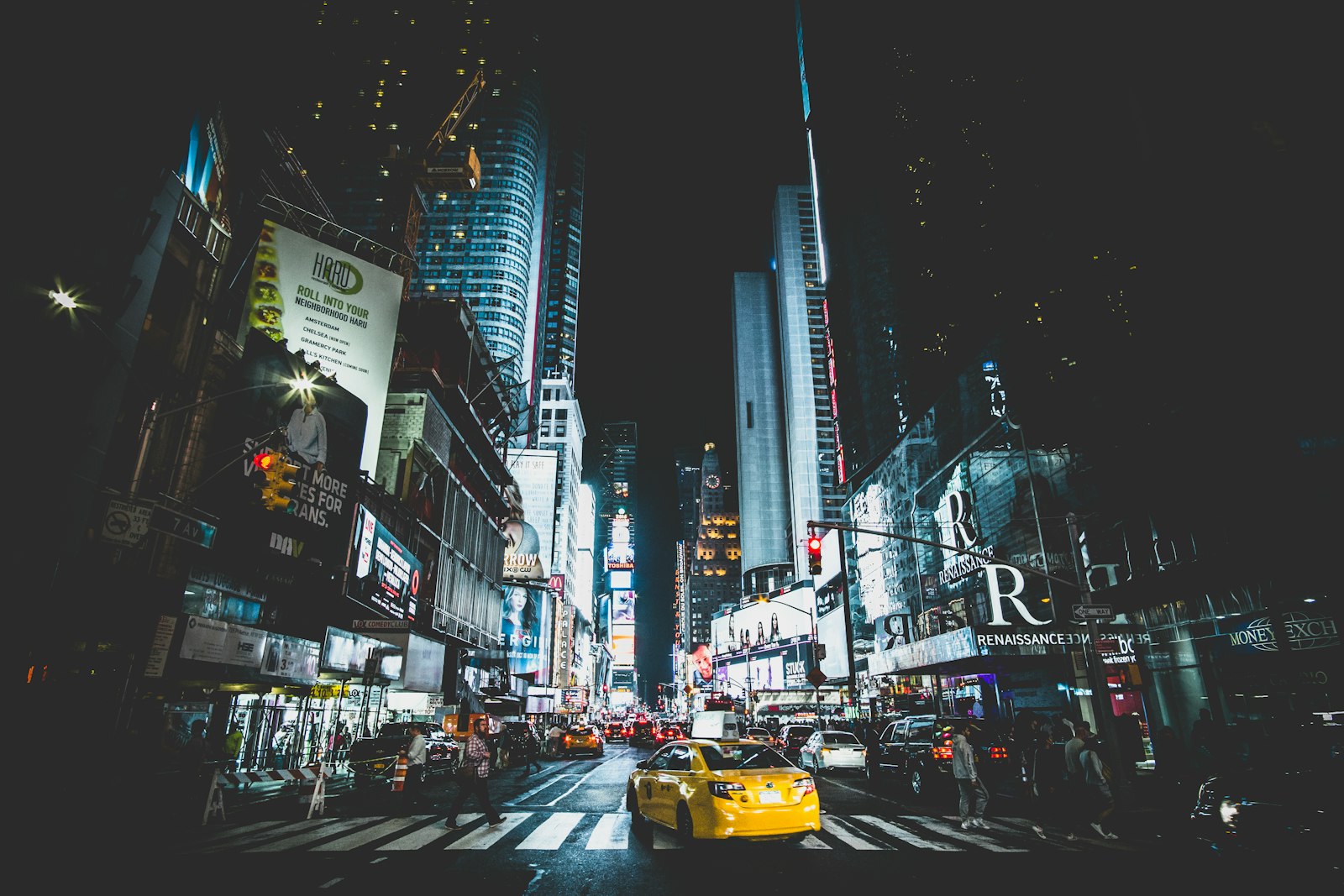 Times Square at night with a yellow cab crossing